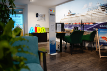 Innenraum mit Sitzgruppe und AIDA-Dekoration in einem Kreuzfahrtbüro.